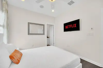 a white bedroom with a bed and a sign on the wall at LAKE VILLA 6bd, all un-suite, pool, spa, grill in Kissimmee