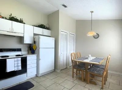 a kitchen with a table and a white refrigerator at 2950 COTTAGE GROVE COURT ORLANDO 3BED in Orlando