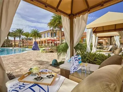 an outdoor patio with tables and umbrellas next to a pool at Luxury Townhome Near Disney w/ Resort Amenities in Orlando