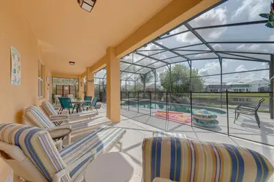 a screened in porch with chairs and a swimming pool at 5 Bedroom private pool home in Veranda Palms in Kissimmee