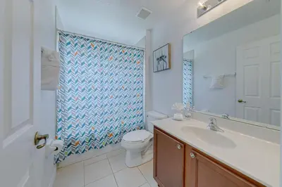 a bathroom with a toilet and a sink and a mirror at 5 Bedroom private pool home in Veranda Palms in Kissimmee