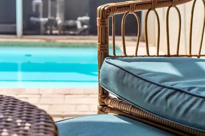 a wicker chair sitting next to a swimming pool at Magical serenity 3 bedroom pool home in Orlando