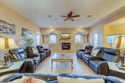 a living room with leather furniture and a ceiling fan at Luxury Pool Home - Disney View in Orlando
