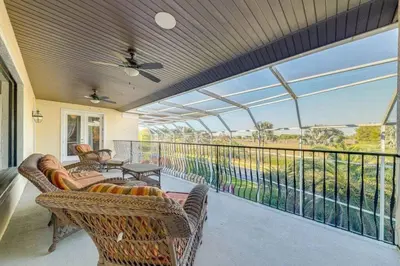 a screened in porch with wicker chairs and a table at Luxury Pool Home - Disney View in Orlando