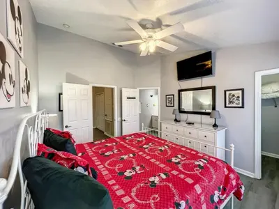 a bedroom with a bed with a red blanket at Mickey's Play House: Family Fun & Comfort in Kissimmee