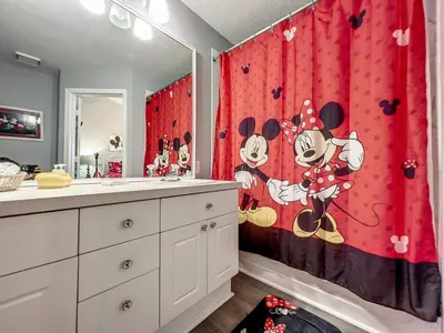 a bathroom with a red shower curtain with mickey mouse on it at Mickey's Play House: Family Fun & Comfort in Kissimmee