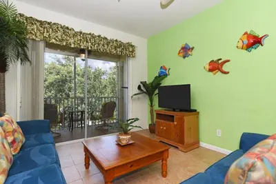 a living room with a blue couch and a tv at Orangebaum Condo: 8 Min to Disney + Resort Perks in Kissimmee