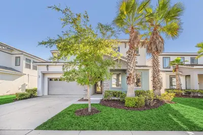 a house with palm trees in front of a driveway at DREAM VILLA 6bd, all en-suite, pool, spa, grill, theatre in Kissimmee