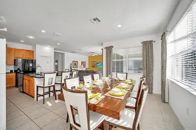 a dining room and kitchen with a table and chairs at DREAM VILLA 6bd, all en-suite, pool, spa, grill, theatre in Kissimmee