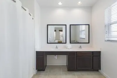 a bathroom with two sinks and two mirrors at Regal Oaks Retreat: Pool, Hot Tub & Near Disney in Kissimmee