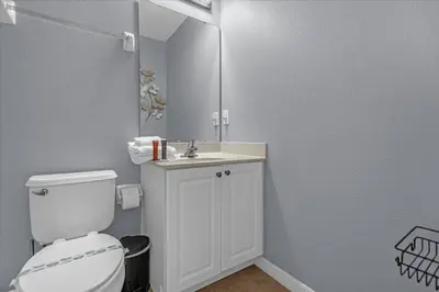 a bathroom with a toilet and a sink and a mirror at Spacious 7-Bedroom Home at Bella Vida Resort with Conservation View in Kissimmee