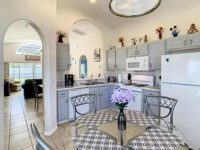 a kitchen with white cabinets and a table with flowers on it at Relax Away Villa: Private Pool Home Near Disney in Orlando