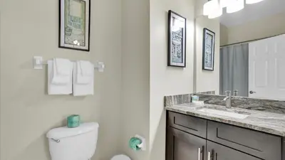 a bathroom with a toilet and a sink and a mirror at FP8176 Windsor Palms Resort Vacation Home in Kissimmee