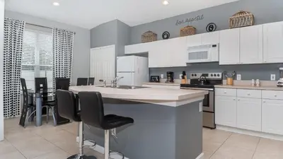 a kitchen with white cabinets and a table and chairs at FP8208 Windsor Palms Resort Vacation Home in Kissimmee