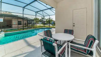 a patio with a table and chairs next to a swimming pool at FP8147 Windsor Palms Resort Vacation Home in Kissimmee