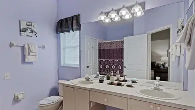 a bathroom with two sinks and a toilet and a mirror at FP8159 Windsor Palms Resort Vacation Home in Kissimmee
