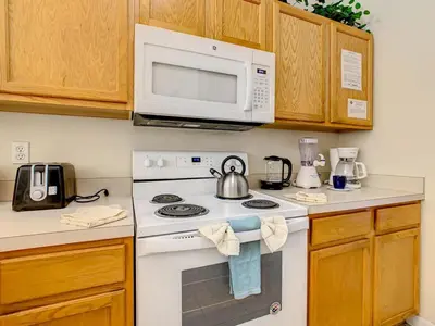 a kitchen with a stove and a microwave at Spacious Emerald Escape - 12 Mins to Disney in Kissimmee