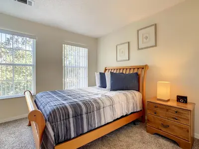 a bedroom with a bed and a dresser and a window at Spacious Emerald Escape - 12 Mins to Disney in Kissimmee