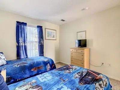 a bedroom with two beds and a television and a dresser at Spacious Emerald Escape - 12 Mins to Disney in Kissimmee