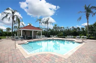 a large swimming pool with chairs and palm trees at Spacious Emerald Escape - 12 Mins to Disney in Kissimmee