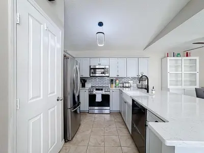 a kitchen with white cabinets and a refrigerator at Stunning 5BR 5Bath Home, Pool, Spa, By Disney in Kissimmee