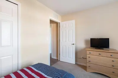 a bedroom with a bed and a tv on a dresser at Spacious Regal Oaks Retreat - Steps to the Pool in Orlando