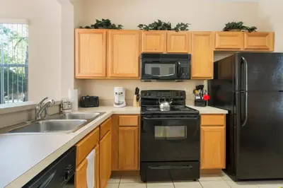 a kitchen with black appliances and wooden cabinets at Spacious Regal Oaks Retreat - Steps to the Pool in Orlando