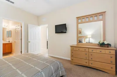a bedroom with a bed and a dresser and a mirror at Spacious Regal Oaks Retreat - Steps to the Pool in Orlando