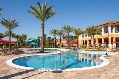 a swimming pool with palm trees in a resort at Spacious Regal Oaks Townhome by Disney in Orlando