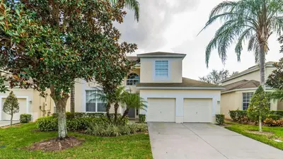a house with a garage and palm trees at CW7730 Windsor Hills Resort Vacation Home in Orlando