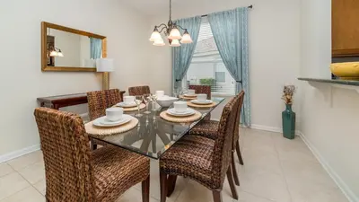a dining room with a glass table and chairs at Amazing 5 BR Home with Pool Windsor Hills Resorts in Orlando