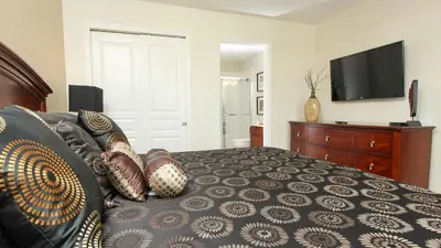 a bedroom with a bed and a dresser with a television at Luxury 6 BR in Windsor Hill Resorts in Orlando