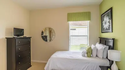 a bedroom with a bed with a dresser and a window at Lavish 4BR Home in Windsor Hills Resort in Orlando