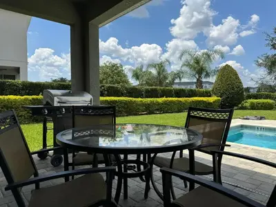 a patio with a table and chairs and a grill at Luxury 6BD Encore Resort Disney Pvt Pool Game Room Near Disney Water Park in Orlando