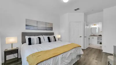 a white bedroom with a large bed with two lamps at BF 2Bedrooms 2303 - 102 in Kissimmee
