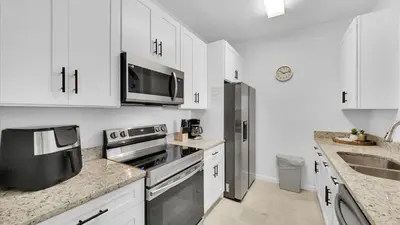 a kitchen with white cabinets and a stainless steel refrigerator at BF 2Bedrooms 2303 - 102 in Kissimmee