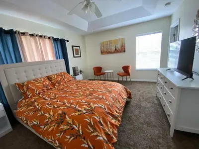 a bedroom with a bed and a desk with a television at Home Near Disney Private Pool & Playground in Howey in the Hills
