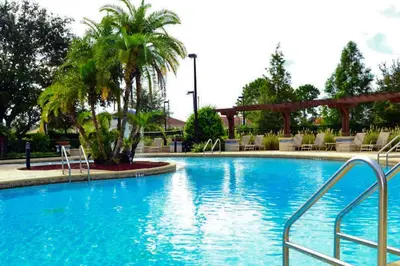 a large swimming pool with palm trees and chairs at Villa Rios Camilo - Lucaya Village in Kissimmee