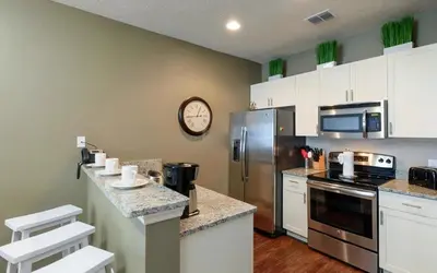 a kitchen with stainless steel appliances and a clock on the wall at Villa Magic- Lucaya Villa Resort in Kissimmee