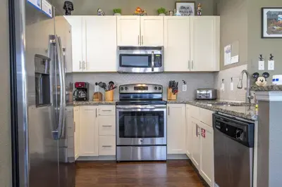 a kitchen with white cabinets and stainless steel appliances at Villa Hakuna Matata- Lucaya Village Resort in Kissimmee