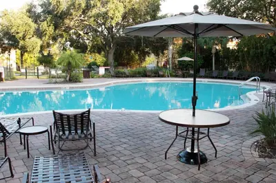 a table with an umbrella next to a pool at Villa Compass- Compass Bay in Kissimmee