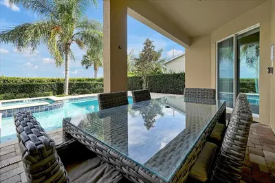 a dining table and chairs next to a swimming pool at 261 LASSO DRIVE 6BED in Orlando