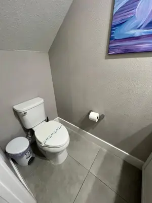 a bathroom with a toilet and a painting on the wall at Disney here we go in Orlando