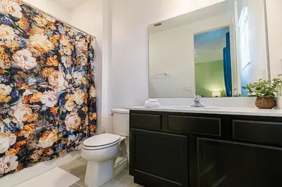 a bathroom with a toilet and a floral shower curtain at 2476 SHANTI DRIVE 12BED in Kissimmee