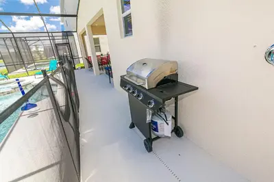 a grill on the side of a building next to a pool at 2476 SHANTI DRIVE 12BED in Kissimmee
