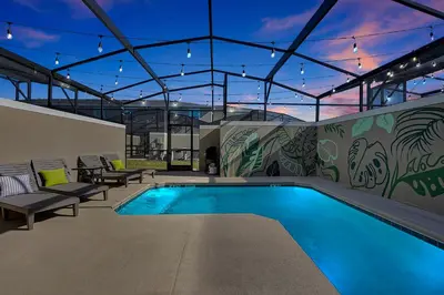 a swimming pool with benches and a building with lights at Top Rated 4BR home in Kissimmee