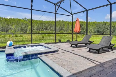 a swimming pool with two chairs and an umbrella at 2968 PENELOPE LOOP 10 BED in Kissimmee