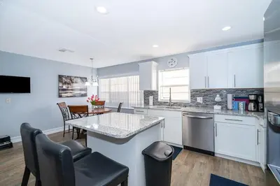 a kitchen with white cabinets and a table and chairs at 4820 JAMAICA LANE 4BED in Kissimmee