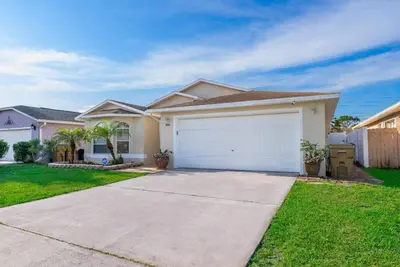 a house with a white garage in a yard at 4820 JAMAICA LANE 4BED in Kissimmee