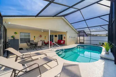 a patio with a swimming pool with chairs and a table at 4820 JAMAICA LANE 4BED in Kissimmee